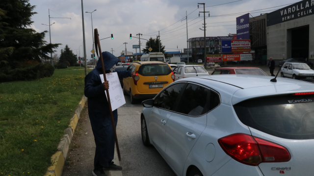 Bir elinde tırpan bir elinde pankartla trafiğe çıkıp sürücüleri uyardı